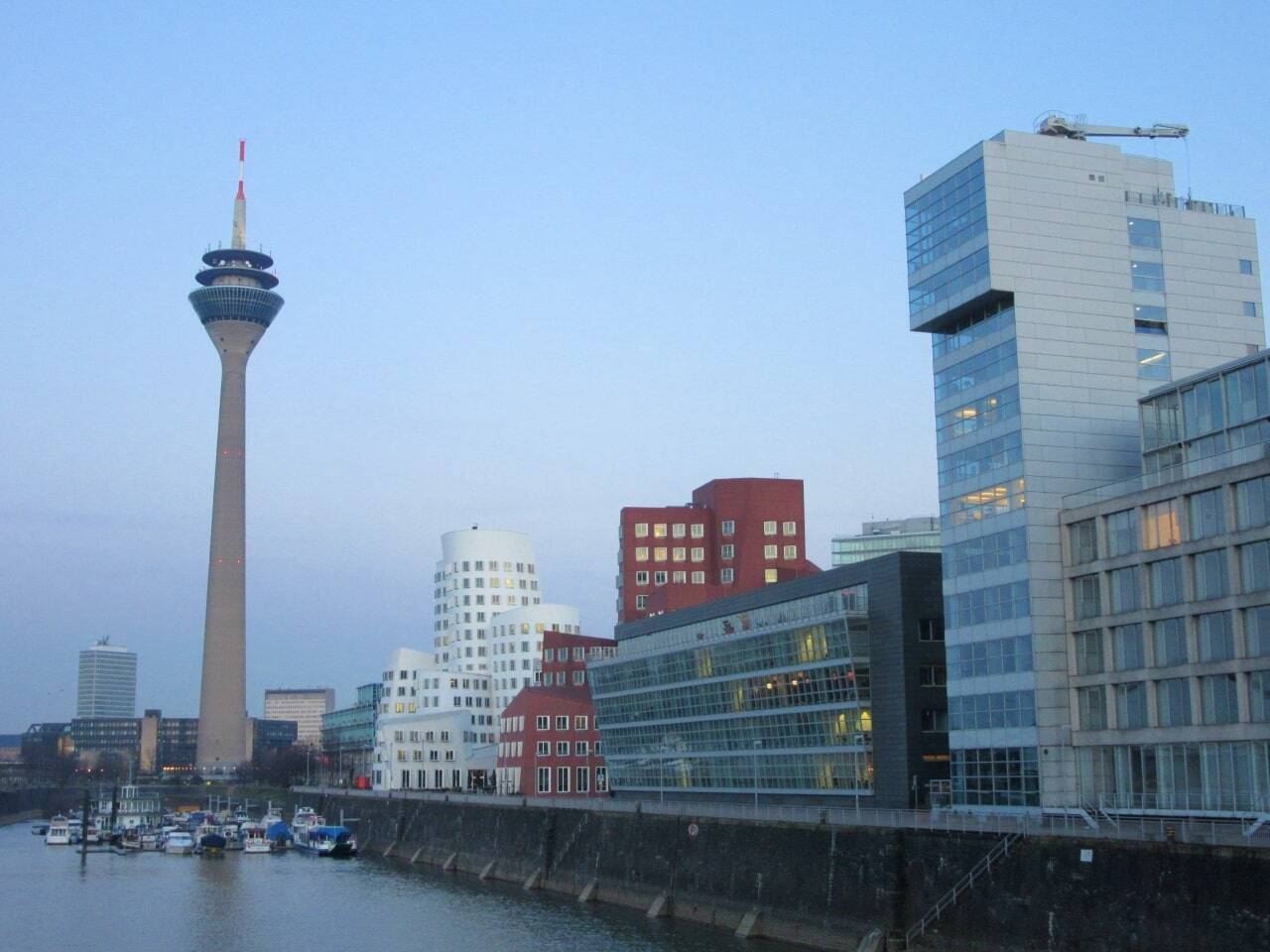 edificios modernistas y gran torre de comunicaciones junto al río al atardecer